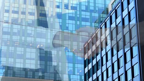 mid section of businessman and businesswoman shaking hands against tall buildings in background