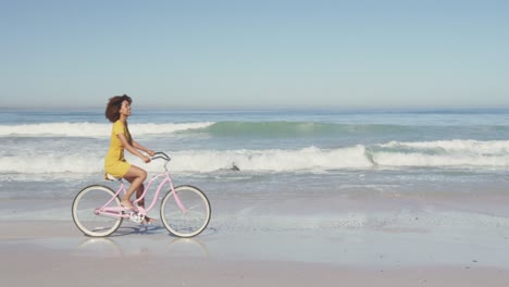 Afroamerikanische-Frau,-Die-Am-Meer-Fahrrad-Fährt