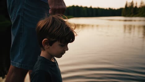 child and parent by a serene lake at sunset