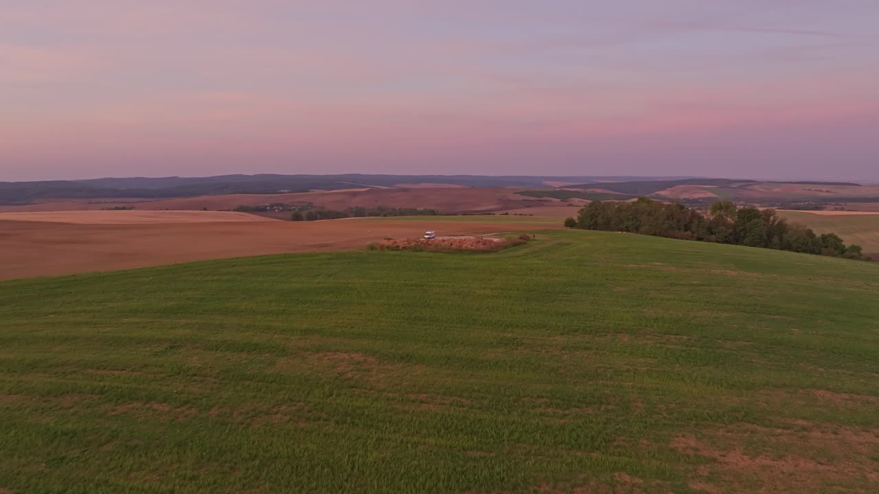 Drone shot of camper resting in golden fields at sunrise, Chvalkovice