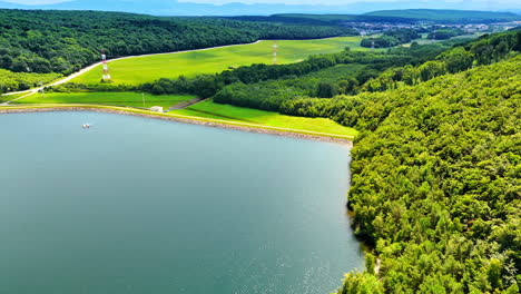 green landscape with lake in europe. lush green fields and forests surround a serene lake, showcasing natural beauty in a peaceful european setting
