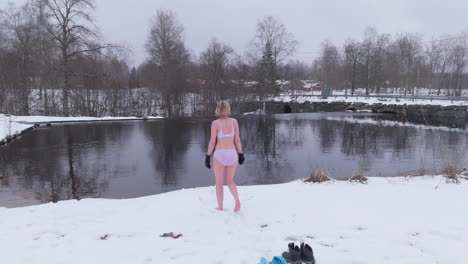 a happy, lively woman stretches before ice bathing in falling snow, sweden