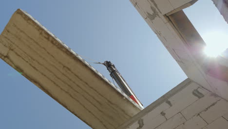 the boom of the crane holds a huge overhead panel over the walls of the house bottom view