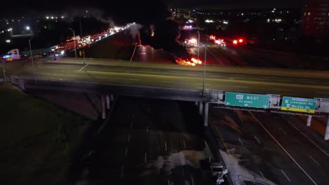 coche en llamas, vehículo en una autopista, calle cerrada y vista desde encima del puente, emergencia de accidente automovilístico, imágenes de drones, zoom out, noche, noche