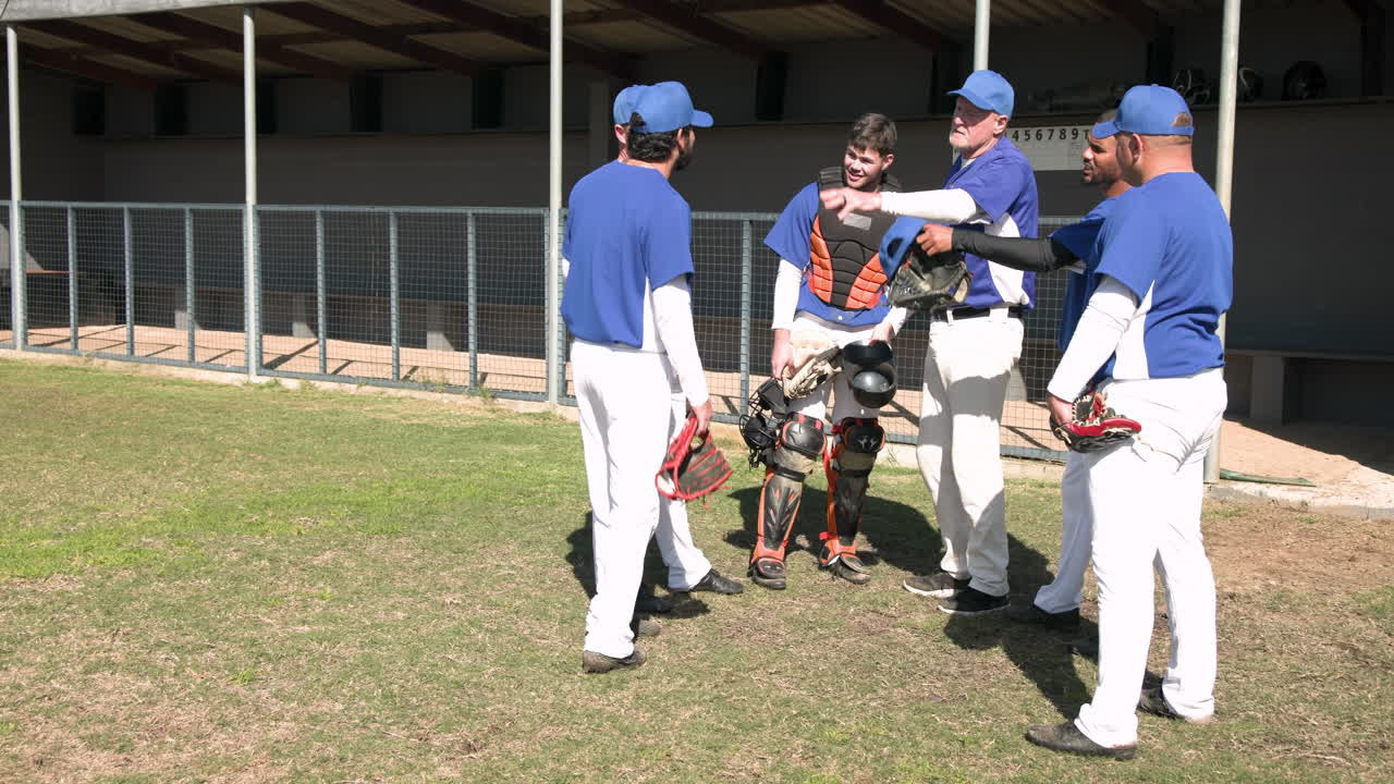 Baseball players in uniforms standing together on field, talking and laughing