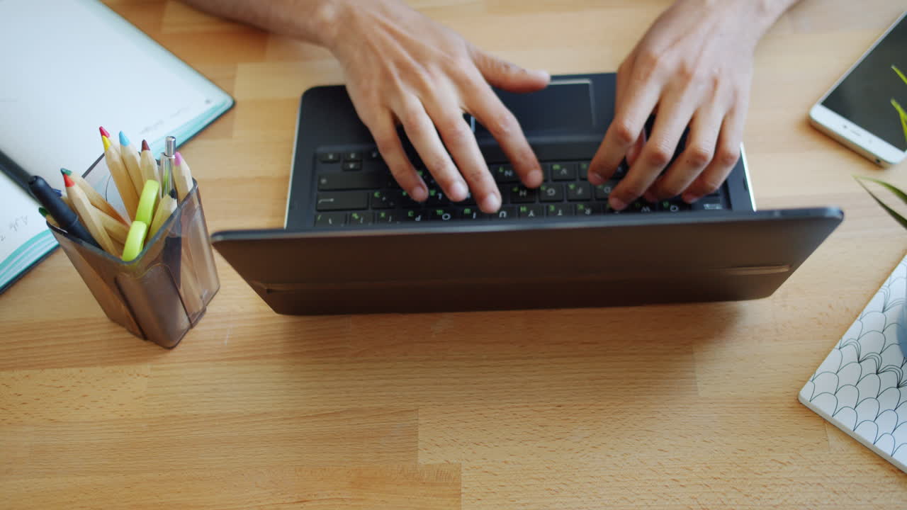 Person working on a laptop at a wooden desk