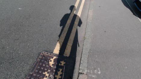 teenager filming his shadow while walking during a sunny day