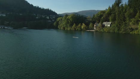 Single-Scull-rowing-boat-with-athlete-training-on-Lake-Bled-in-morning,-aerial