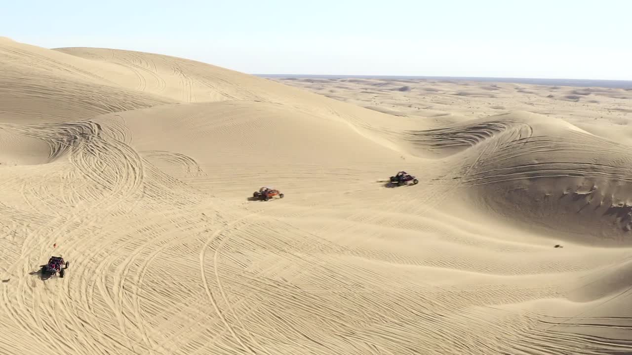 vista aérea de seguimiento, vehículos todo terreno vehículos todo terreno en el desierto conduciendo sobre dunas de arena