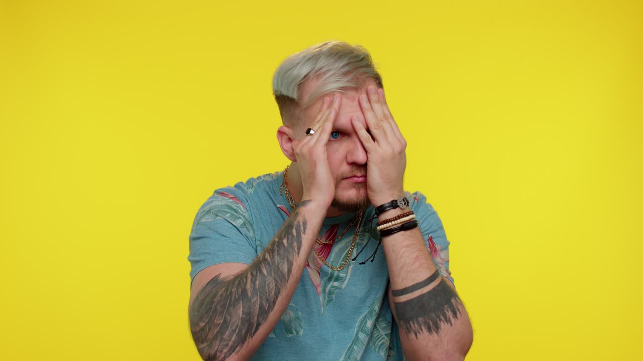 hombre curioso curioso cerrando los ojos con la mano y espiando a través de los dedos, escondiéndose y mirando, buscando