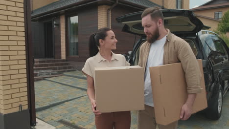 happy couple with boxes posing before new house