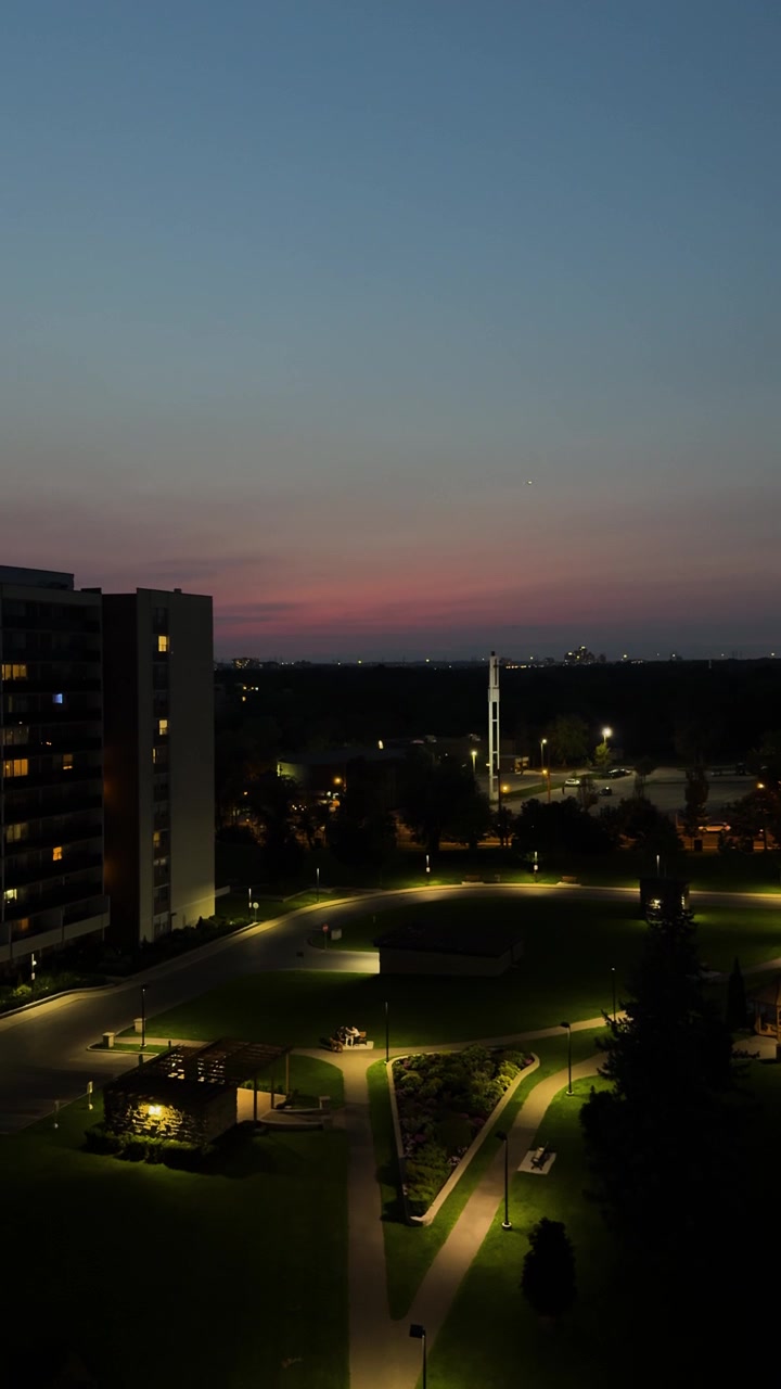 Vista noturna de edifícios residenciais iluminados e caminhos de parque ao anoitecer em North York