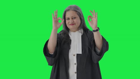 Happy-Indian-senior-female-lawyer-showing-okay-sign-Green-screen