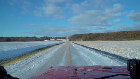 Driver-POV-while-driving-a-snowy-country-road-past-corn-fields-on-a-sunny-late-autumn-afternoon