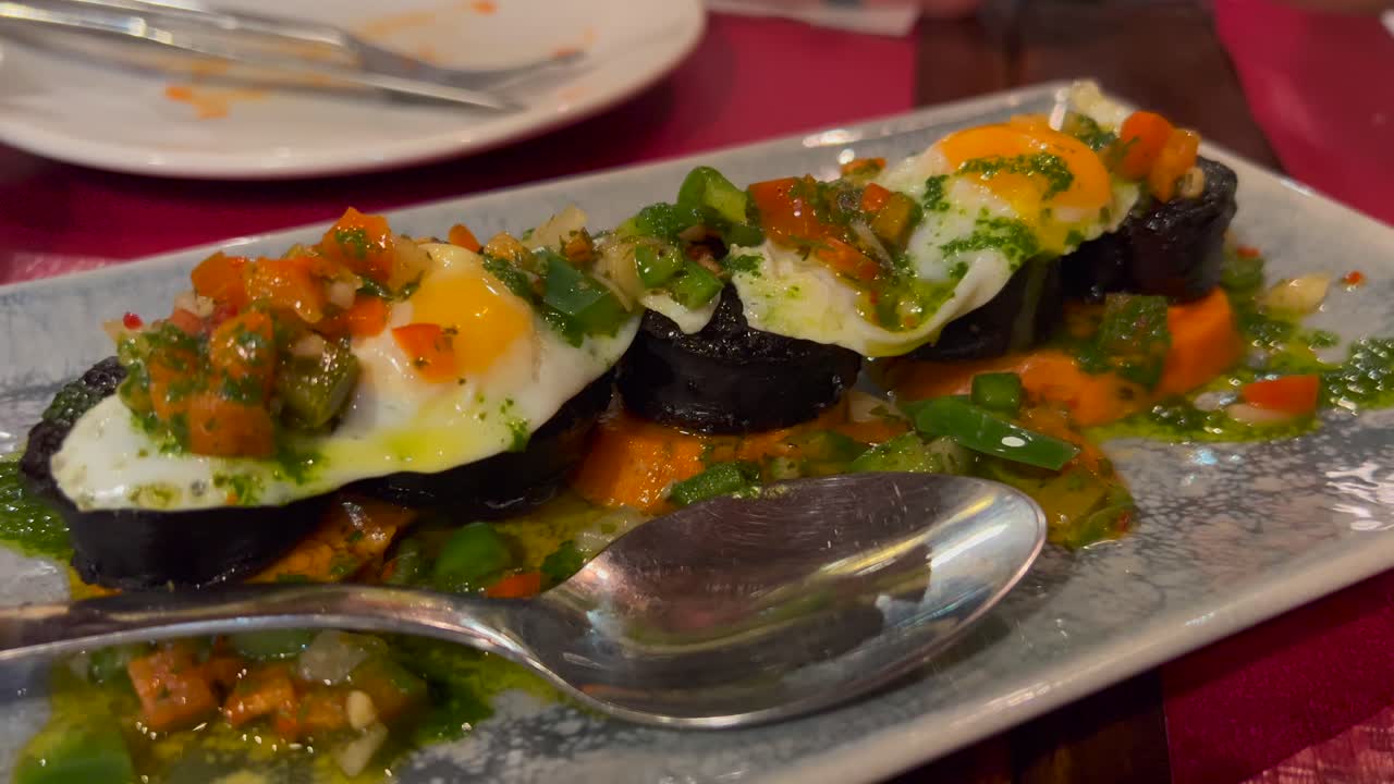 Traditional Spanish blood sausage with vegetables and quail eggs at a tapa restaurant, tapas in Marbella Spain, 4K shot