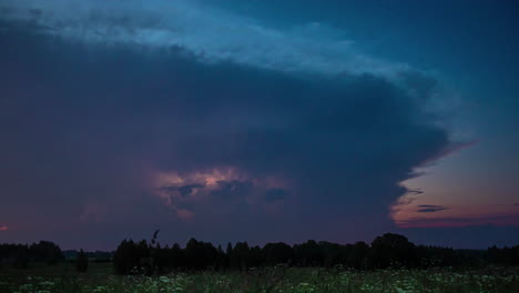 Time-lapse-shot-of-an-epic-thunderstorm-in-the-evening-with-a-view-of-the-flashing-clouds,-passing-black-clouds-and-the-windy-landscape-at-the-blue-hour