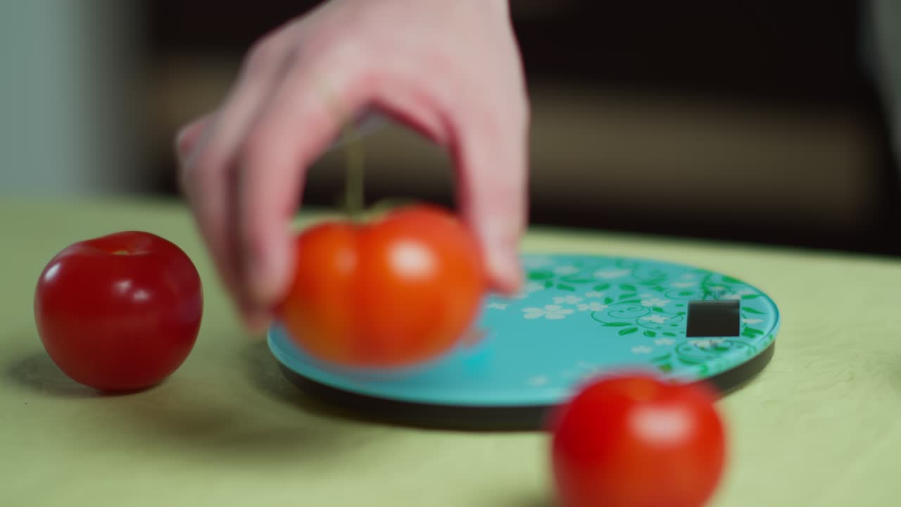 주방 전자 척도 에서 신선 한 토마토 를 무게 로 측정 하는 사람
