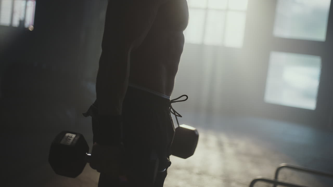 체육관 에서 덤벨 을 들어 올리는 남자