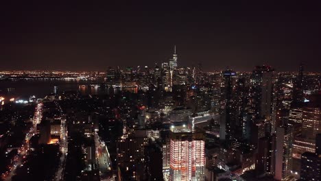 drone footage of the manhattan city skyline at night, taken from brooklyn, new york