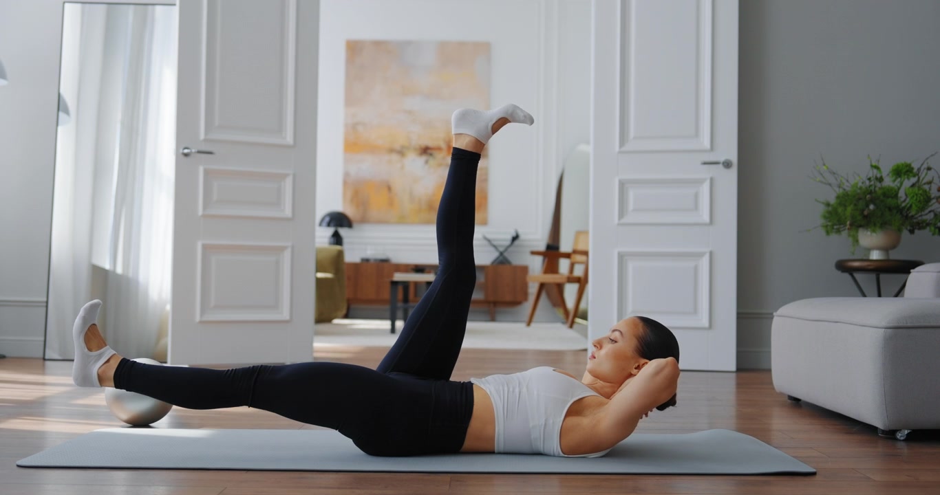 Fit Woman Performing Leg Raises on Yoga Mat in Bright Living Room