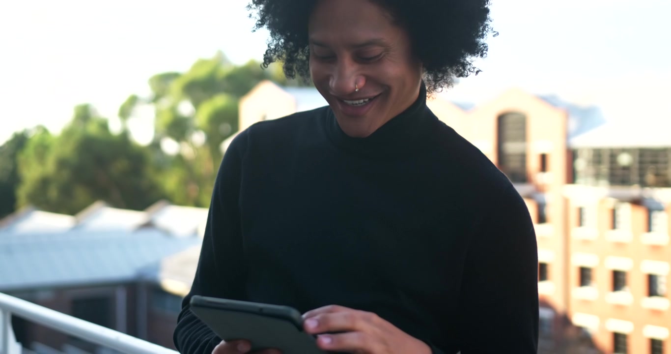 African American man in turtleneck bowing showing tablet tapping swiping reading content on balcony