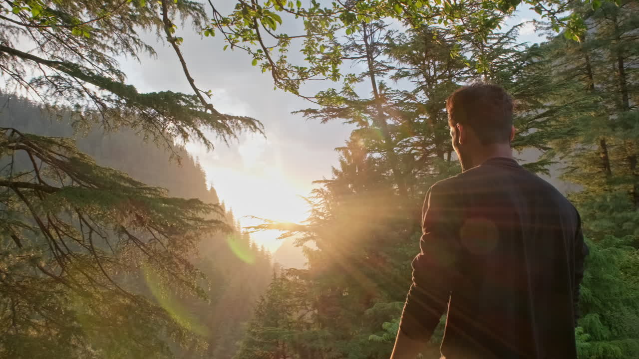 Indian Man enjoying the beautiful view of the sunset at the top of the mountain peak