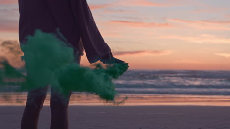 Mujer-Joven-Sosteniendo-Granada-De-Humo-Verde-En-La-Playa-Al-Atardecer