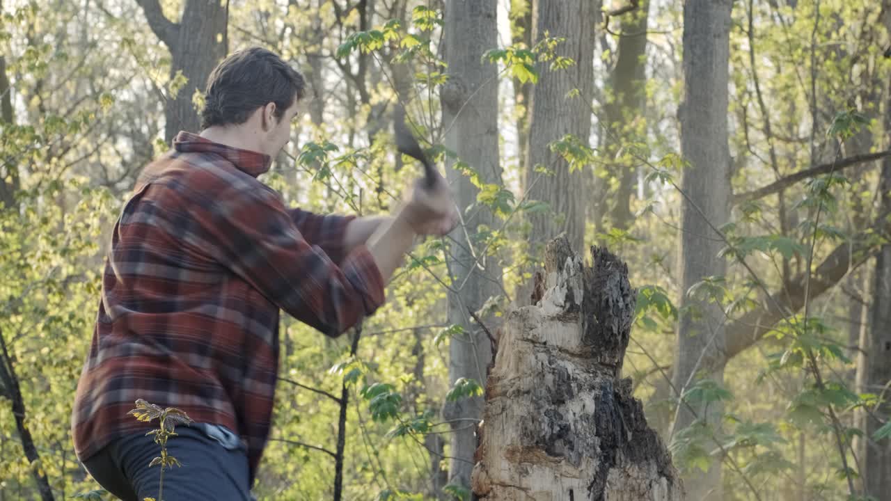 매력적인 젊은 백인 남자가 그의 도끼로 나무 조각을 잘라