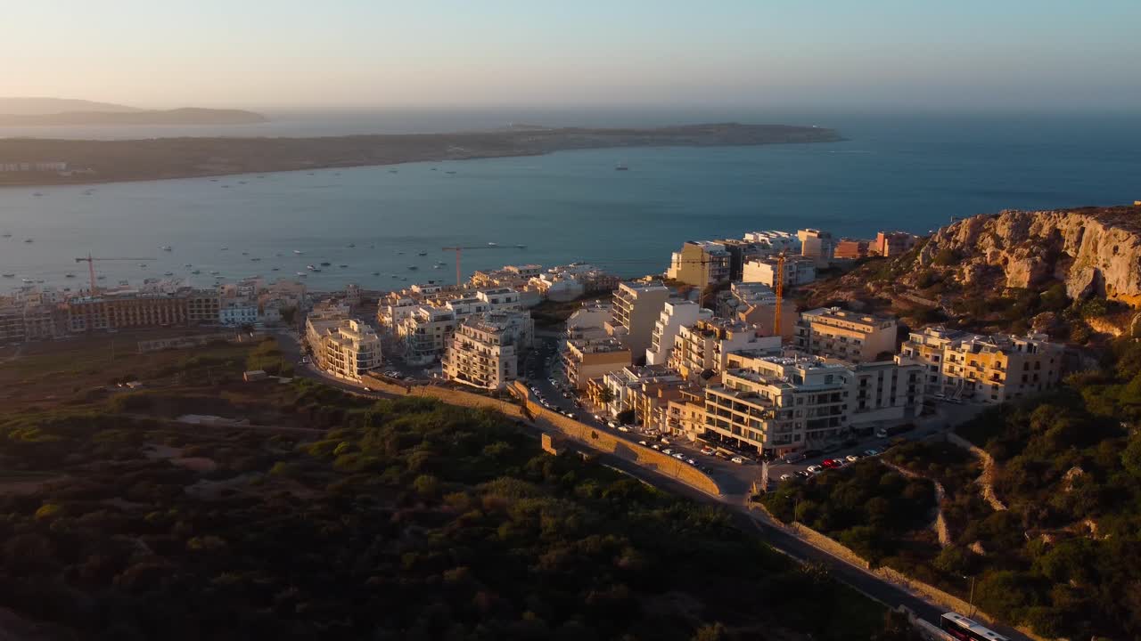 Maltese seaside town of Mellieha at sunset. Aerial panning view