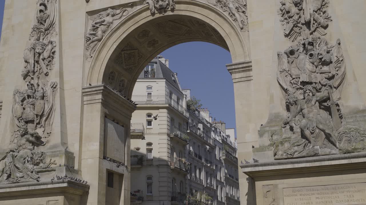 Beautiful archway in Paris with intricate sculptures and pigeons perched above