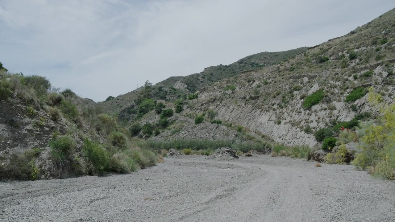 Plano general de bolsas de plástico, lonas y otros tipos de basura provenientes de la agricultura intensiva e invernaderos abandonados en el lecho de un río en España