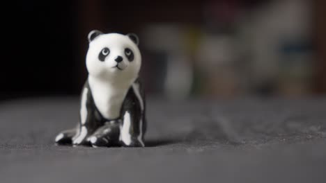 Mano-Recogiendo-Panda-De-Juguete-De-Figurillas-En-Miniatura,-De-Cerca-Con-Fondo-Borroso