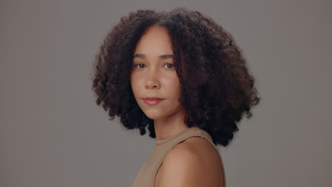 young woman with curly hair posing in studio