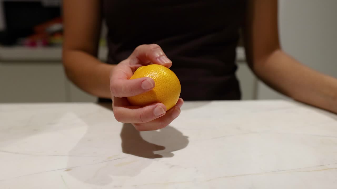 Persona manipulando una naranja sobre una mesa