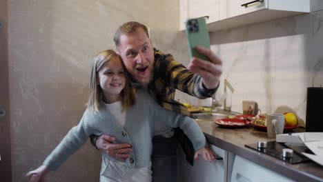 padre e hija tomando una selfie en la cocina