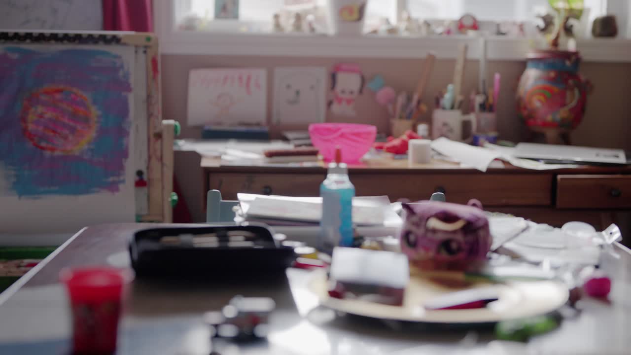 A table is filled with paint, paper and children's toys.