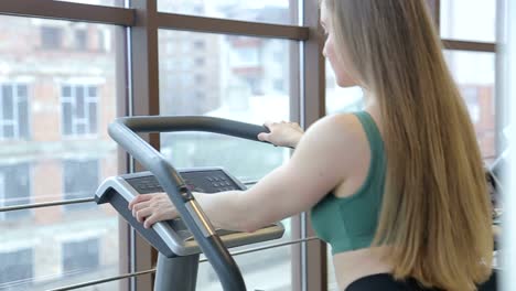 attractive caucasian girl running on the treadmill in the sport gym with earphones attractive caucasian girl running on the treadmill in the sport gym with earphones