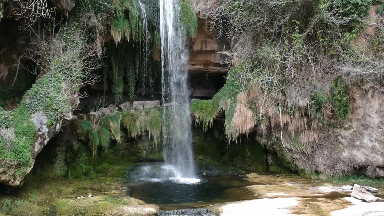 vistas aéreas de una cascada con una cueva y un edificio antiguo en cataluña, españa