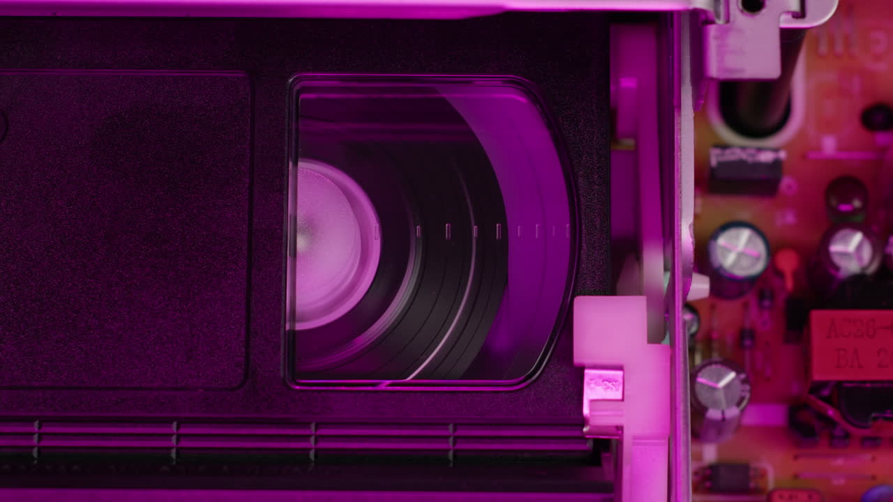 VHS PLAYER, Old video recorder inside in neon pink light close-up, VHS. Retro player in neon blue light, vintage video cassette broadcasting, audio tape.