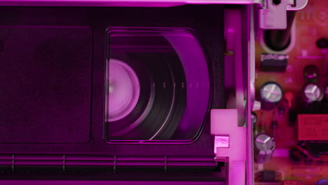 vhs player, old video recorder inside in neon pink light close-up, vhs. retro player in neon blue light, vintage video cassette broadcasting, audio tape.