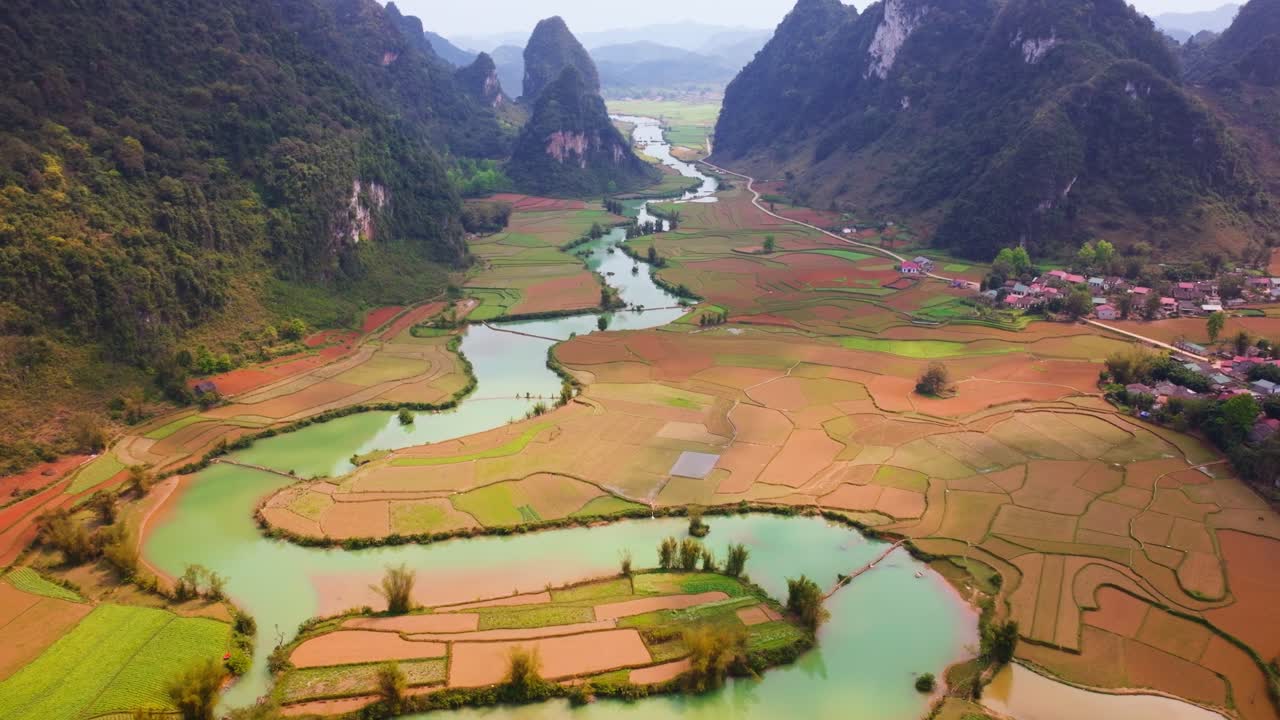 la escena muestra un río sinuoso que atraviesa exuberantes campos de arroz, rodeado de imponentes montañas de piedra caliza.