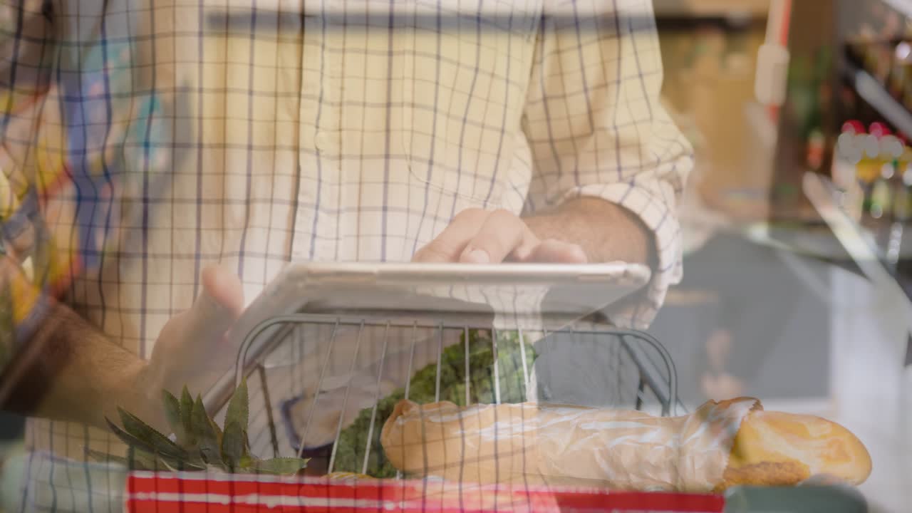 Man tapping tablet above basket in grocery aisle, causing faint data overlay highlighting produce