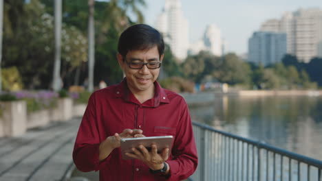 man using tablet in a park by a lake