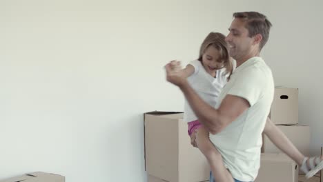 Joyful-dad-holding-daughter-in-arms-and-dancing