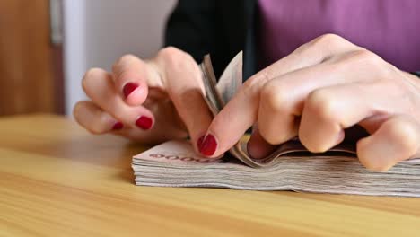 close up of woman with red fingernails counting thai baht banknotes.