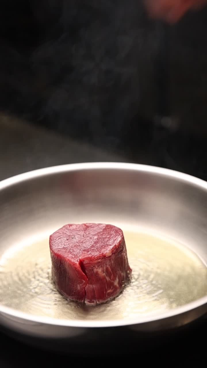 Chef che mette una bistecca di manzo cruda in una padella calda
