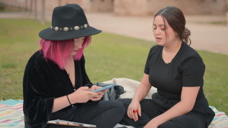 two women having a conversation while doing face painting outdoors