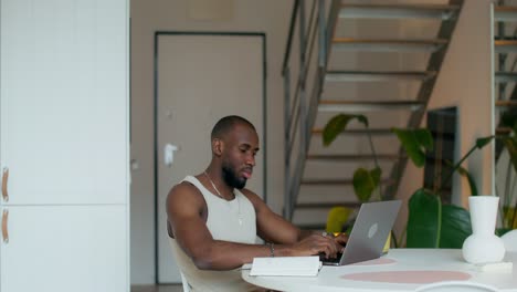 hombre trabajando en una computadora portátil en una mesa de comedor