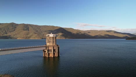 low aerial over the water towards the intake tower at lake eildon, victoria, australia