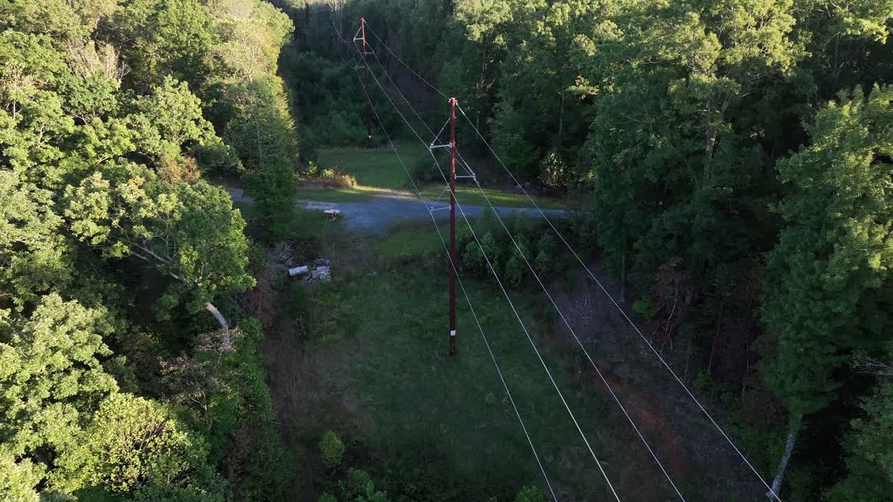 Power poles or electricity pylon between colored trees in America. Golden hour in scenic forest suburb of usa. Aerial top down flyover shot